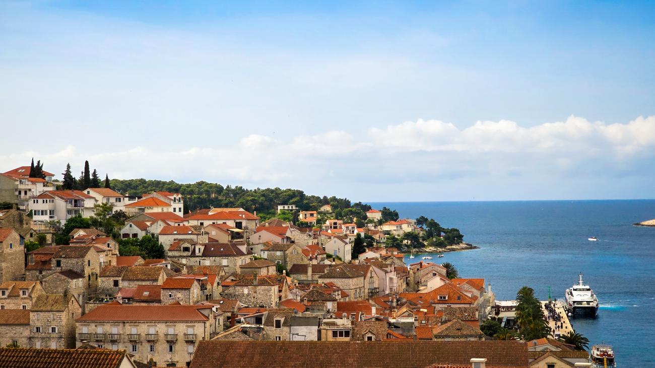 Panoramic view of Hvar old town with orange terracotta rooftops along the Adriatic Sea in Croatia.