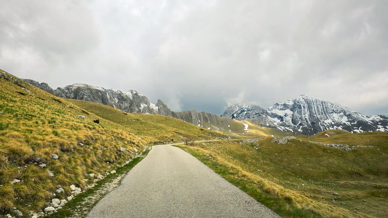 A narrow road stretching into the rugged snow-dusted peaks of Durmitor National Park in Montenegro.