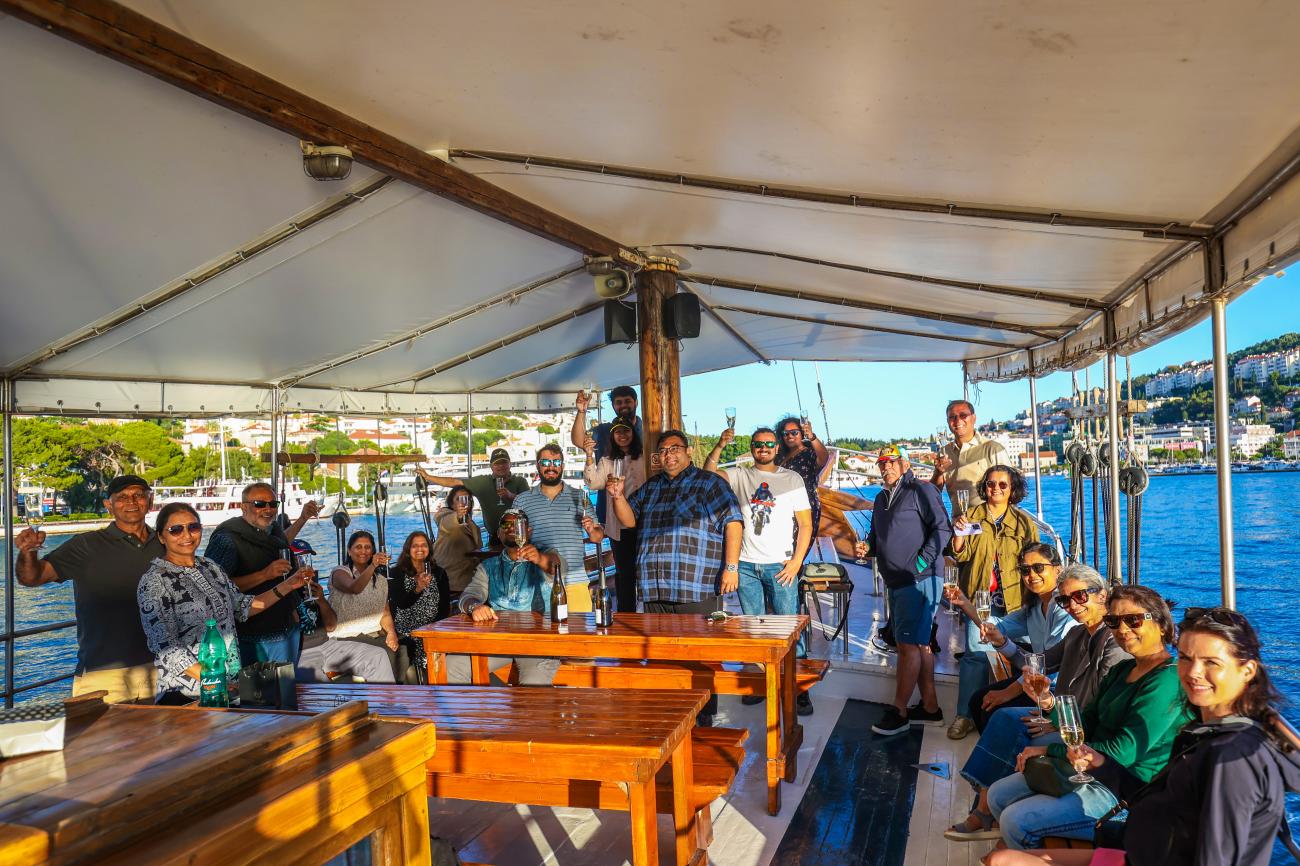 Tour group raising glasses on a covered boat cruise in a sunny Balkan harbour