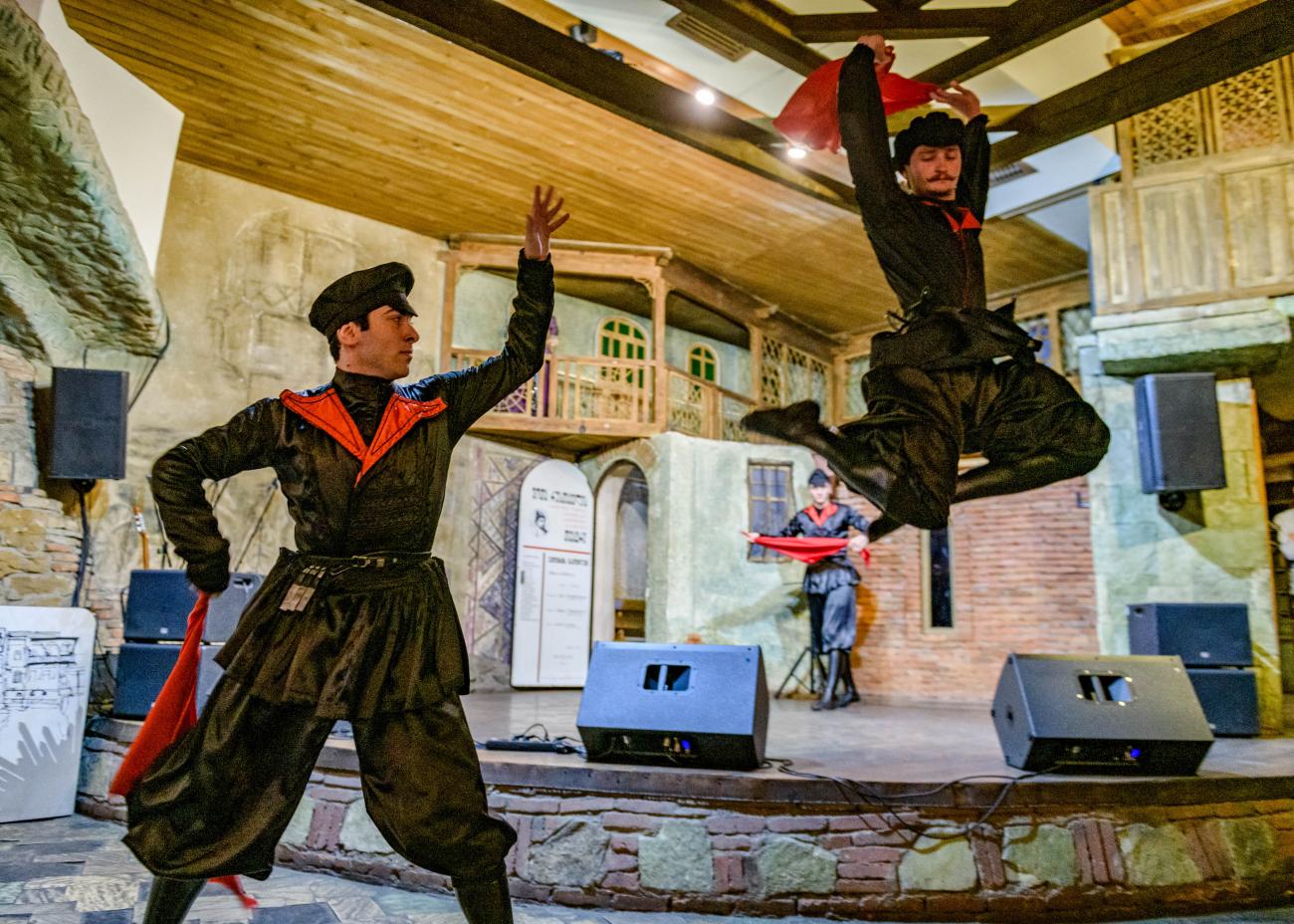 Traditional Georgian dancers performing an energetic Caucasian folk dance on stage.