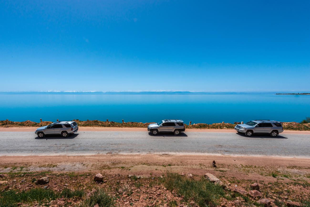 SUVs parked along Issyk-Kul turquoise lake shore