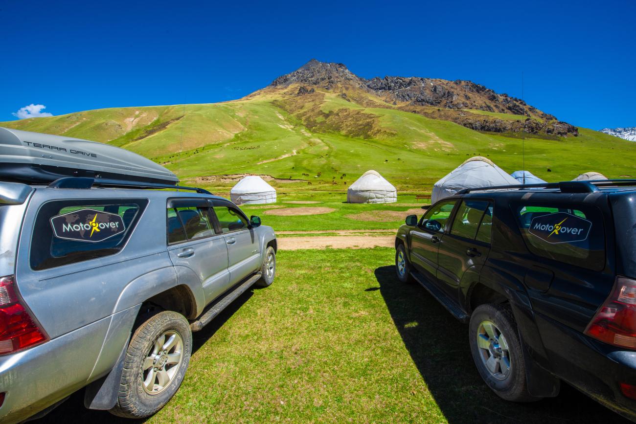 SUV convoy on highway with snowy mountains Kyrgyzstan