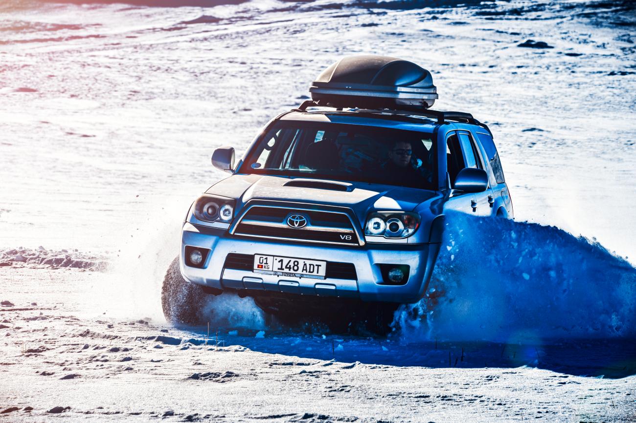 A Toyota 4x4 SUV plowing through deep snow on a winter trail in Kyrgyzstan