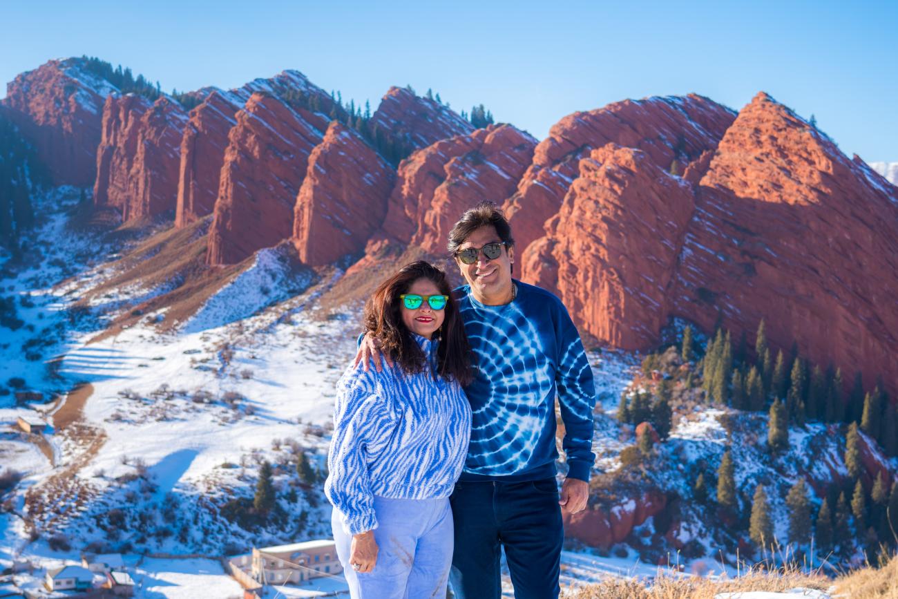 A couple posing in front of the dramatic red rock formations of Jeti-Oguz in winter