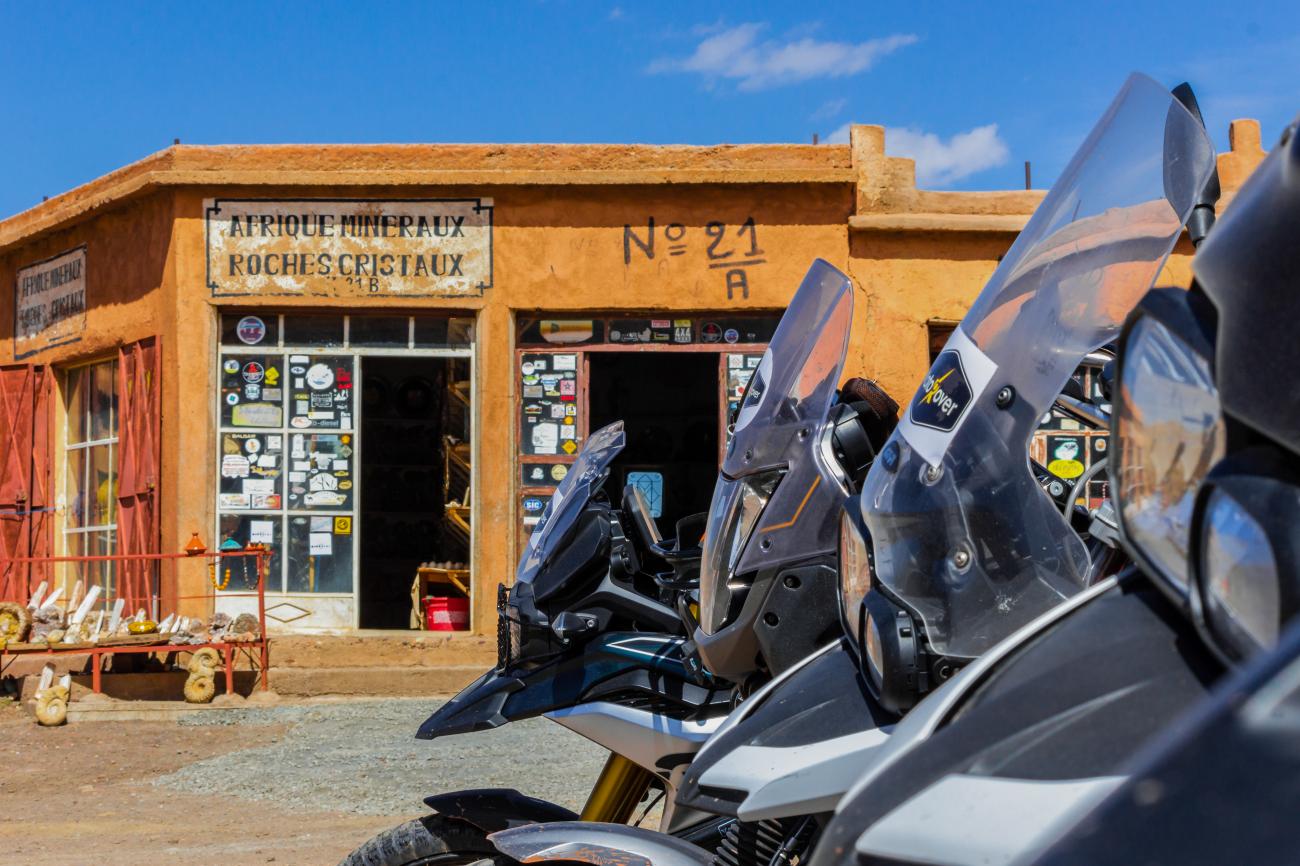 Adventure motorcycles parked outside a traditional mineral and crystal shop in Morocco.
