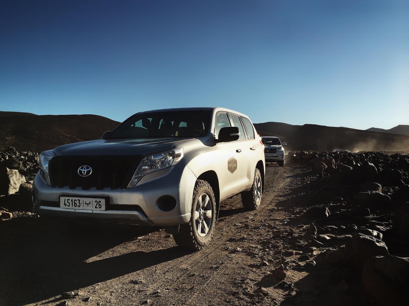 Toyota Land Cruiser navigating a rocky off-road mountain trail in the Moroccan highlands.