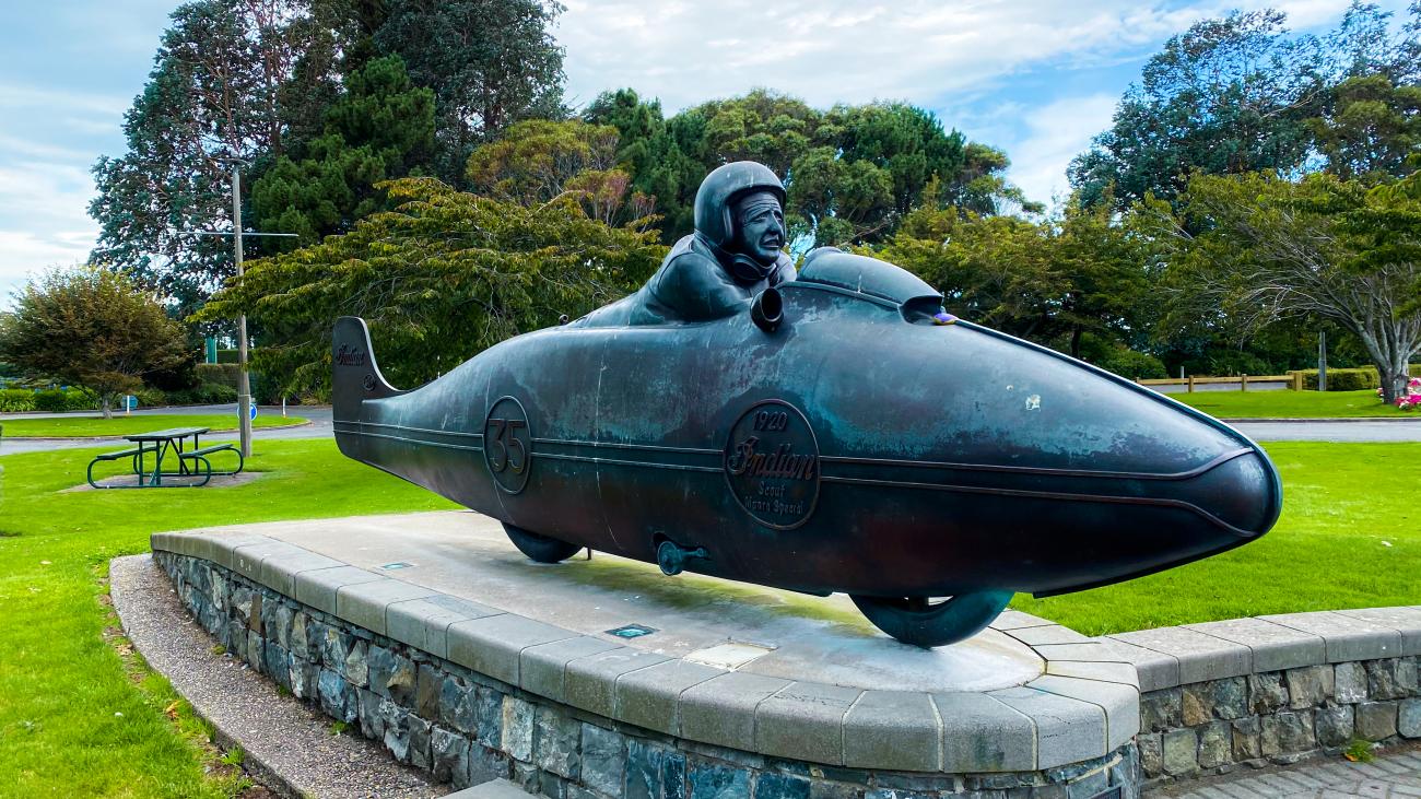 Bronze statue of Burt Munro on his streamlined Indian motorcycle in a park in Invercargill, New Zealand.