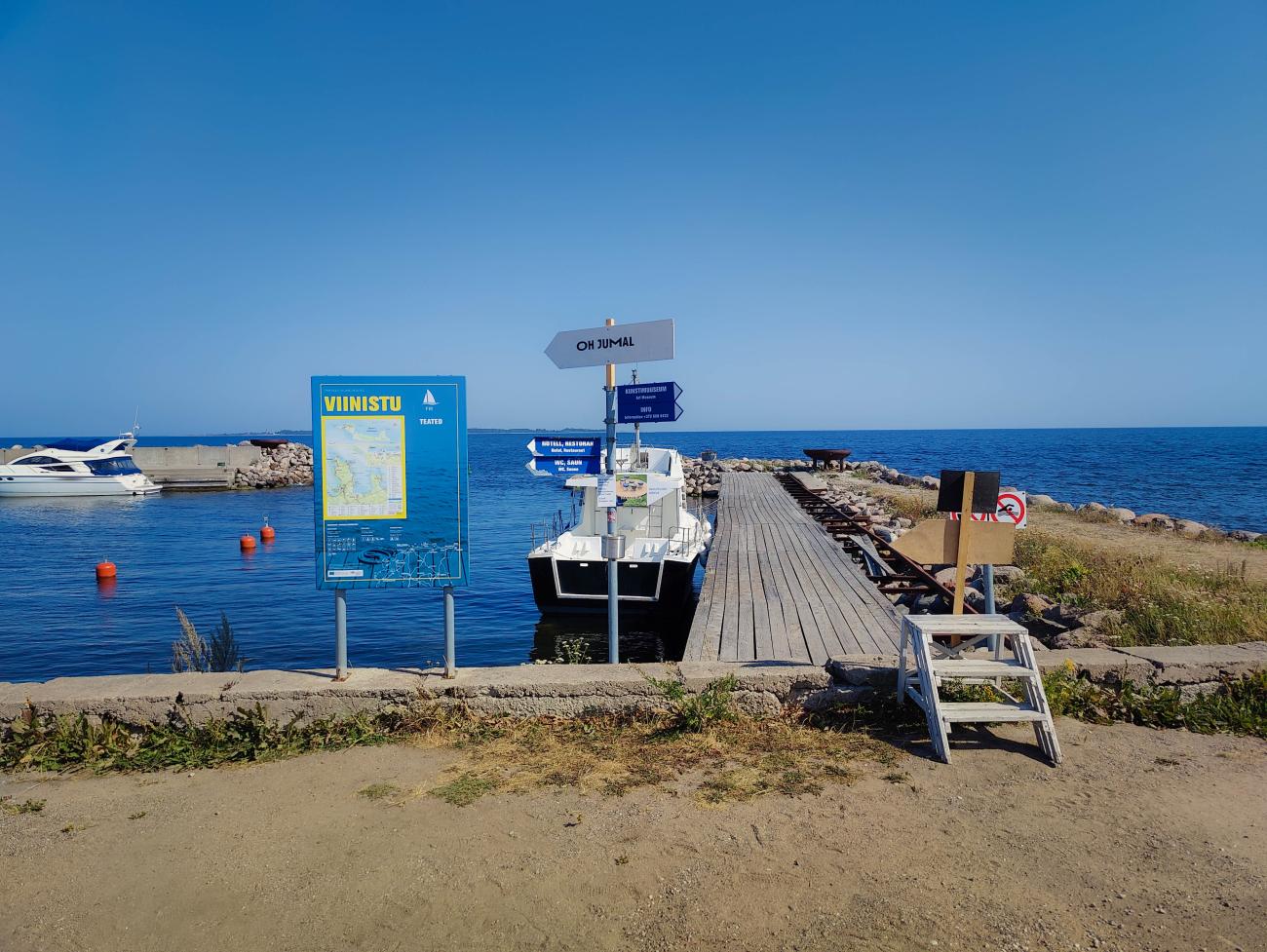 Wooden pier and signpost at Viinistu harbour on the Baltic Sea coast of Estonia.