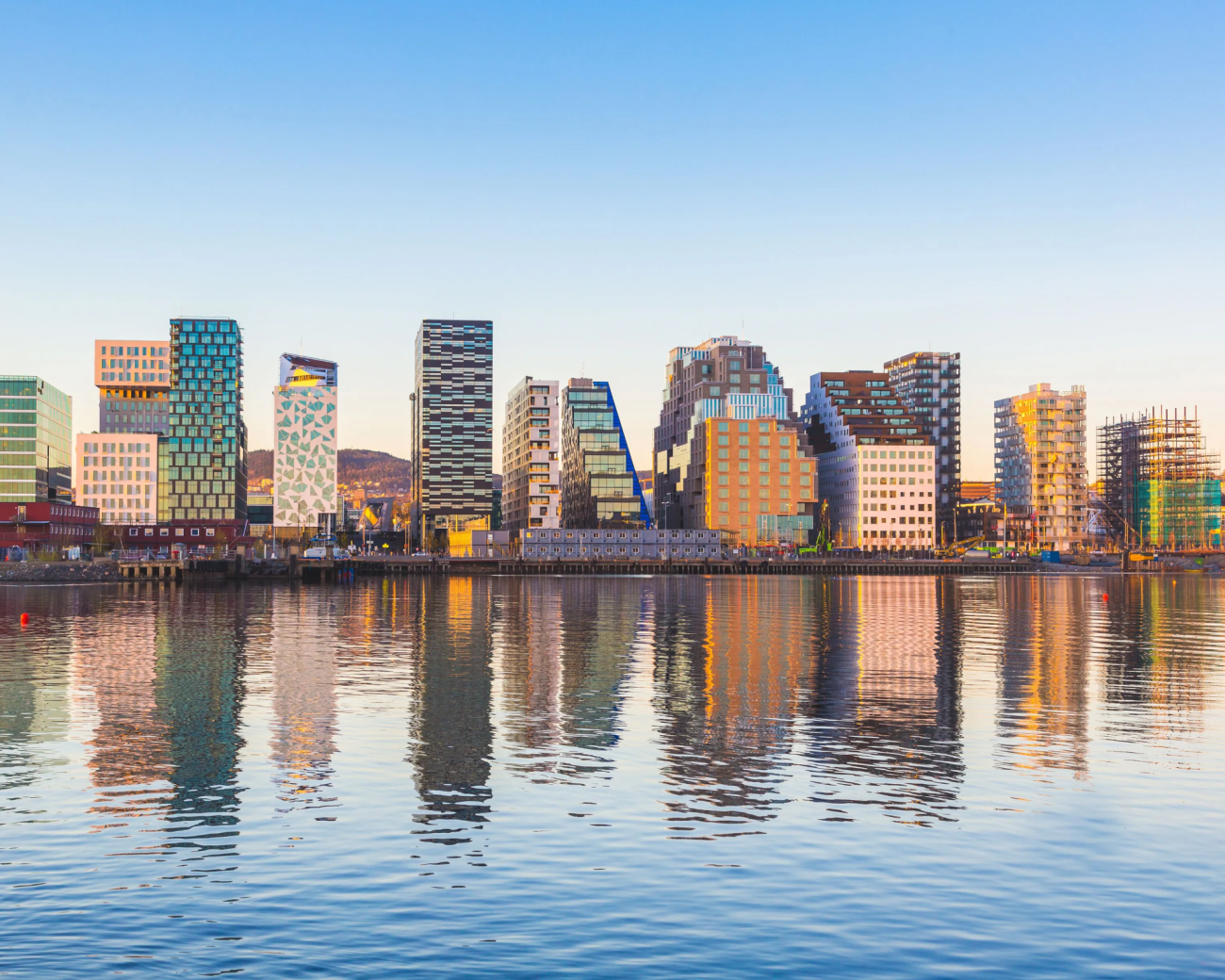Modern Barcode district buildings reflected in the Oslo waterfront on a clear day.