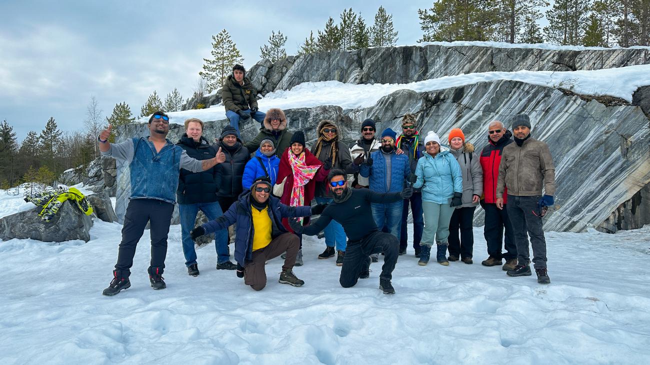 Tour group posing for a photo in front of striking grey marble rock formations at a snow-covered quarry in Karelia.