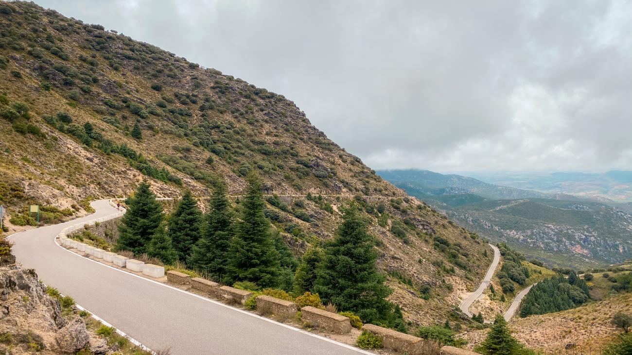 Twisting mountain road with switchbacks cutting through rugged terrain in the Andalucian highlands.