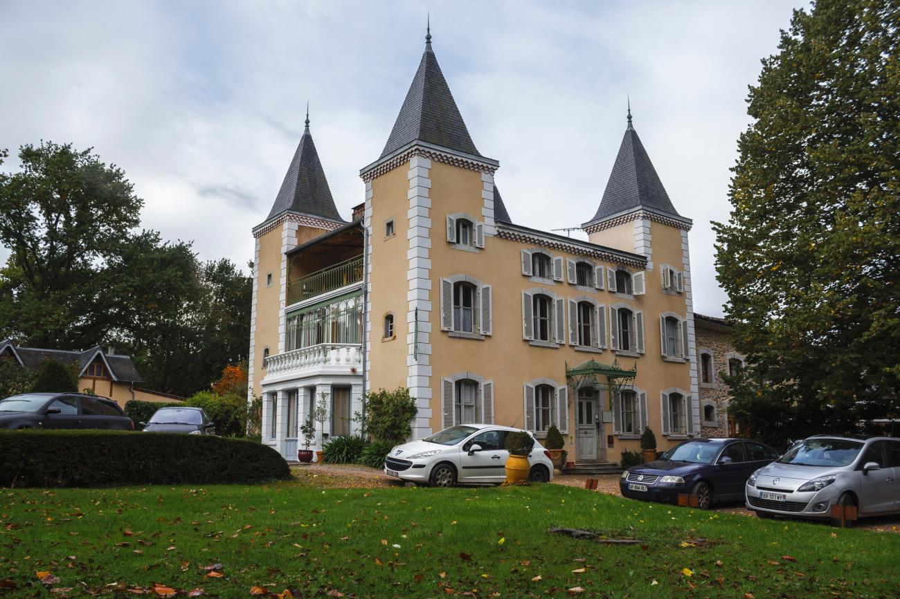 Elegant French chateau hotel with pointed turrets and a manicured green lawn in the countryside.